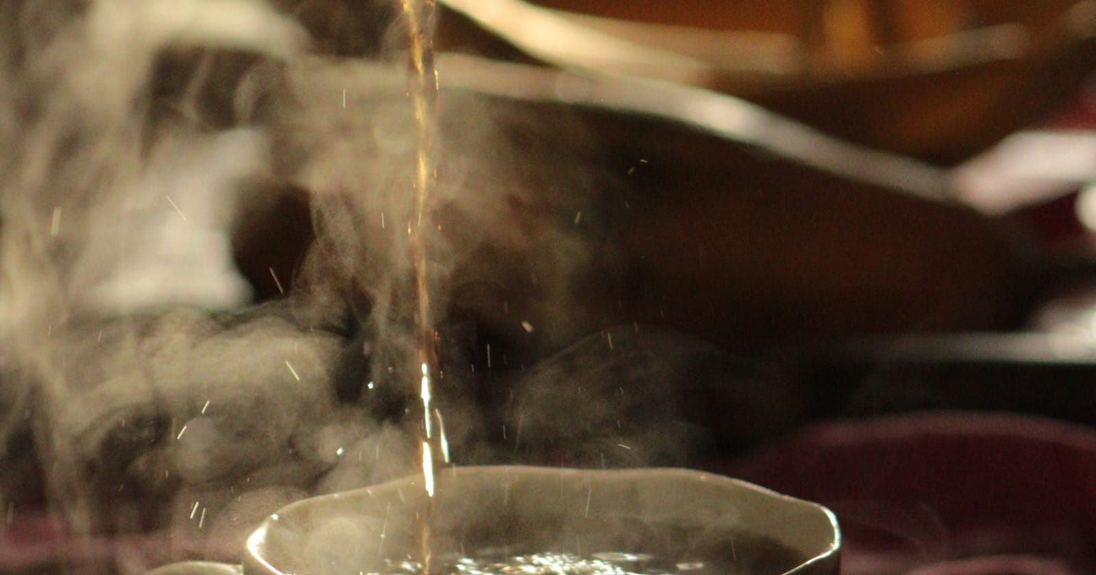 Steaming tea being poured at sunrise, a warming wake-up cue for Kapha mornings