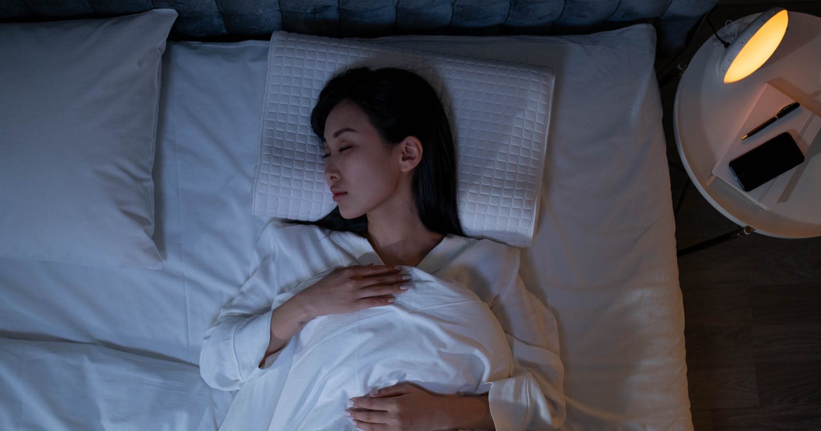 Calm woman resting in dim bedroom light, Vata sleep needs warmth and quiet