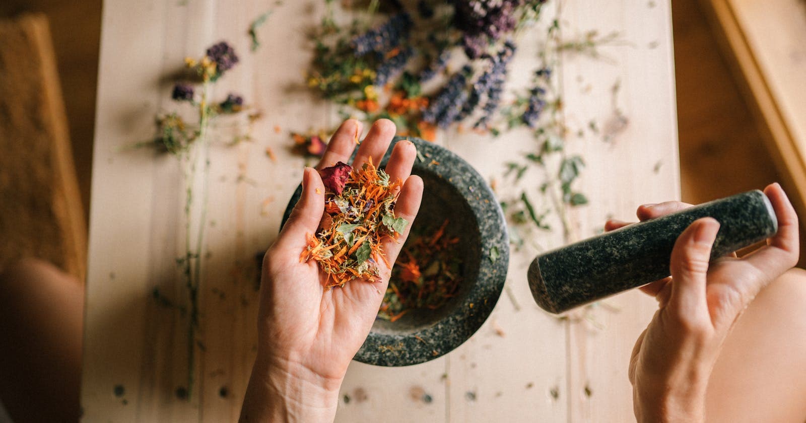 Hands grinding herbs with a mortar and pestle — two ancient herbal traditions side by side