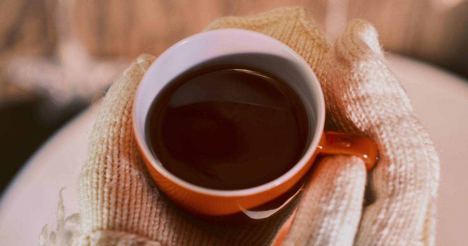 Hands holding a warm tea on a cold day — winter Kapha season needs spice and movement