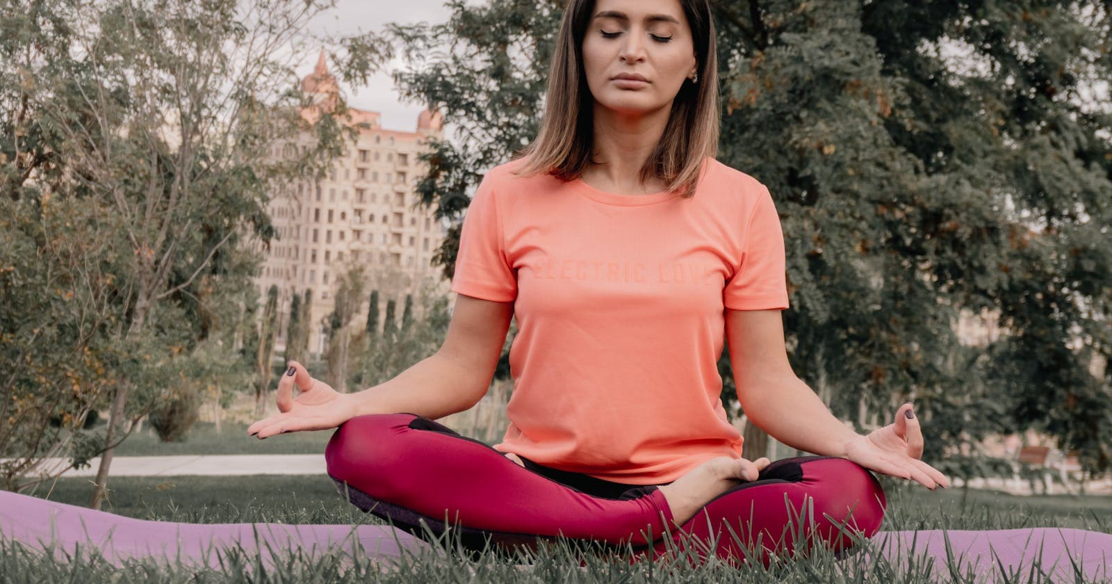 Woman practicing yoga outdoors on grass, strength training that doesn't deplete you