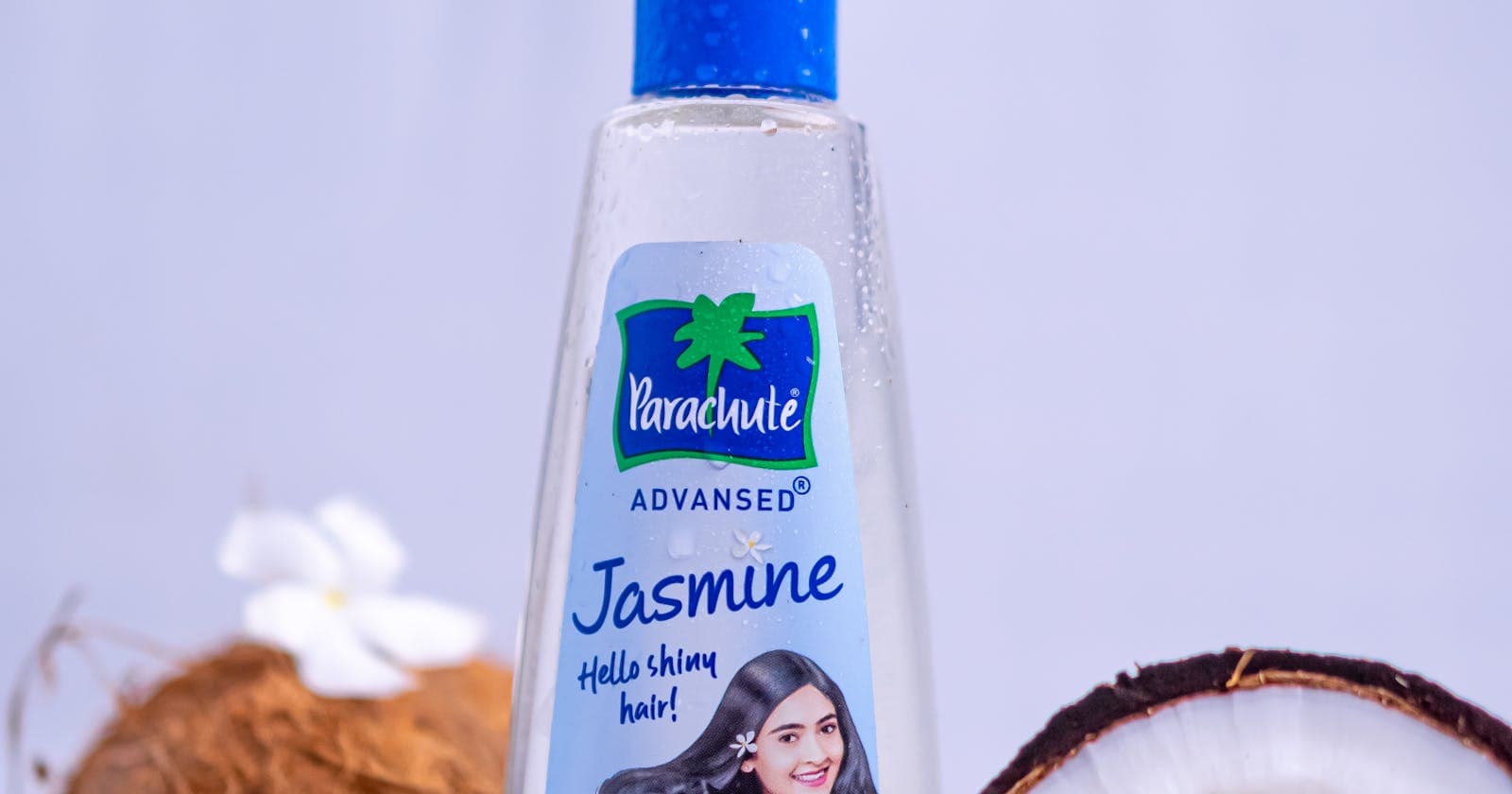 Hair oil bottle beside coconuts and jasmine flowers, Ayurvedic hair nourishment