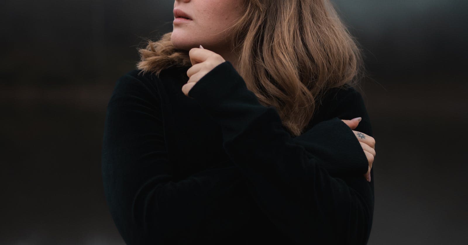 Woman holding herself in soft outdoor light, women's wellness as a long, gentle conversation with the body